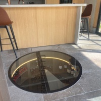 Круглый стеклянный люк с электроприводом и обратной петлей на винтовую лестницу винного погреба - закрытая створка